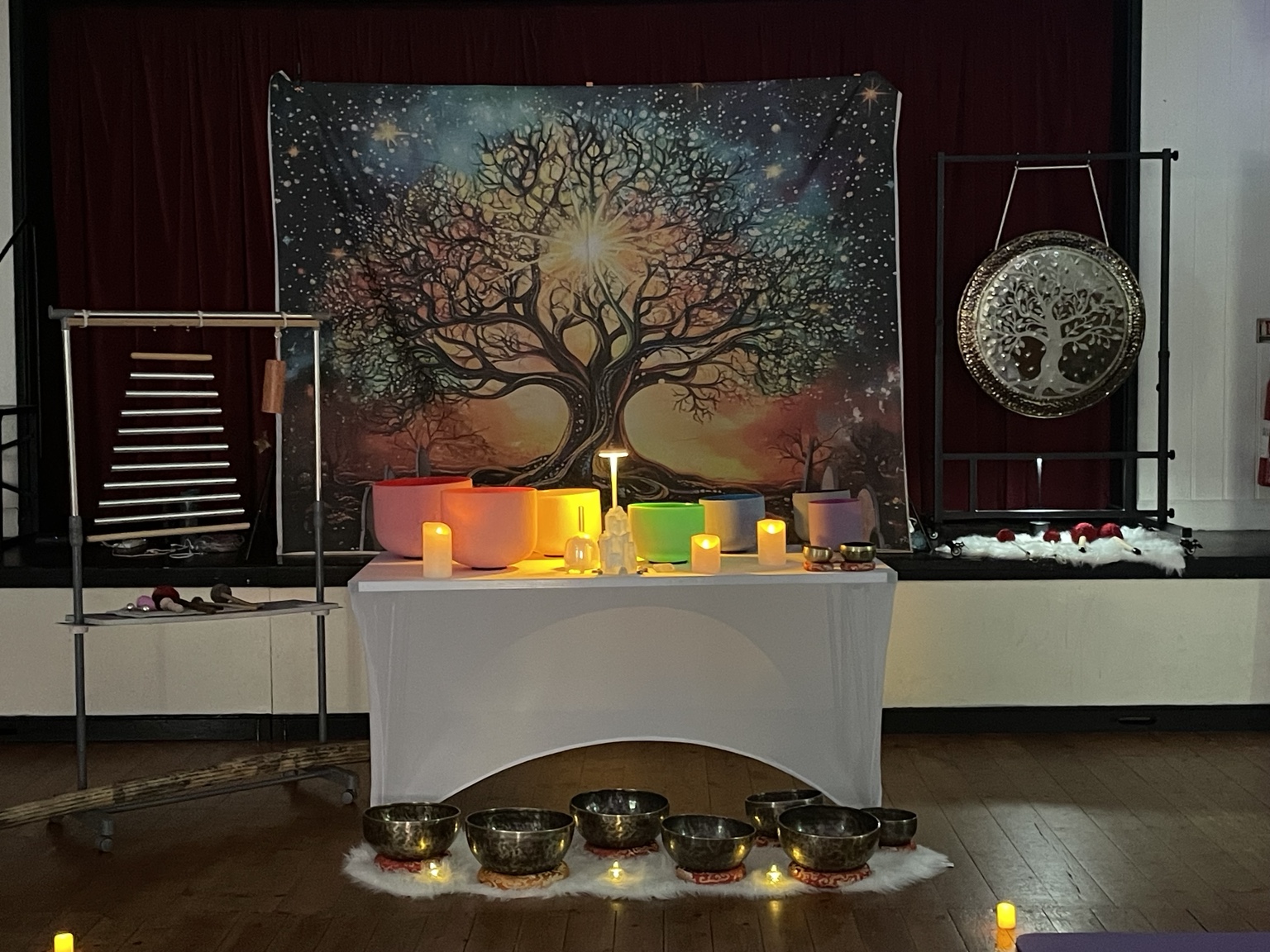 Harmonious Hearts sound bath setting with singing bowls, gong, chimes and warm lights